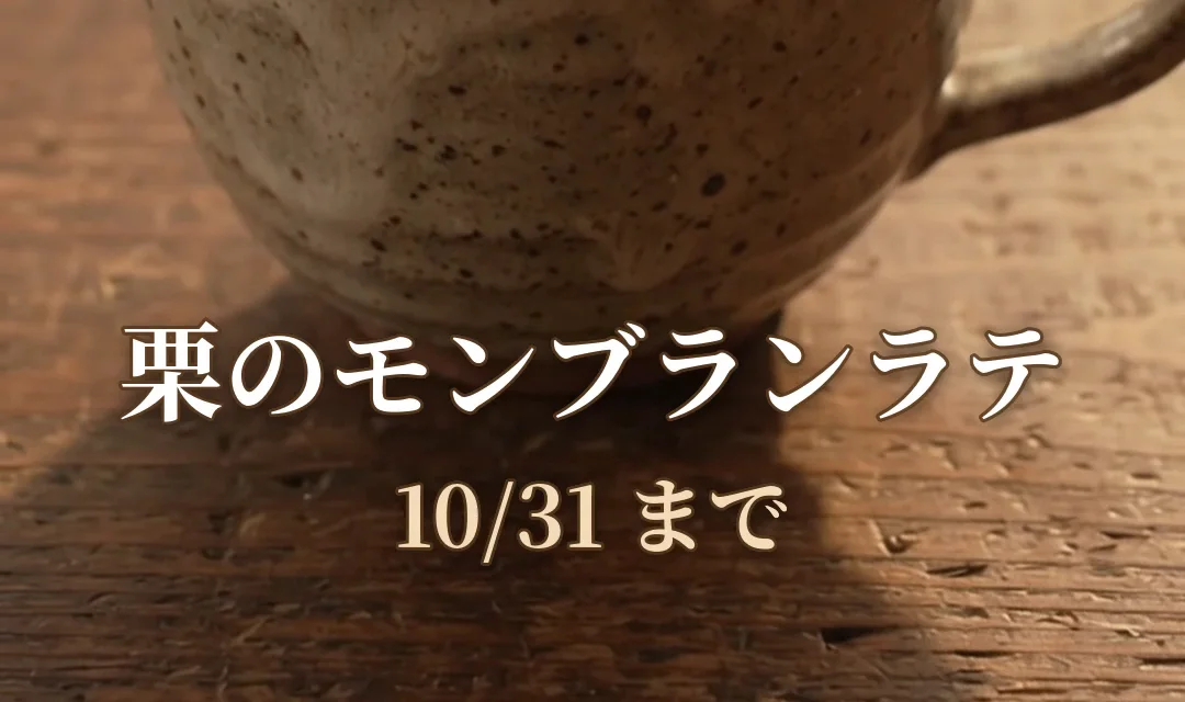 木のテーブルの上の、栗のクリームがのったラテのカップ。下の方に白い明朝体で「栗のモンブランラテ」「10/31 まで」の字幕